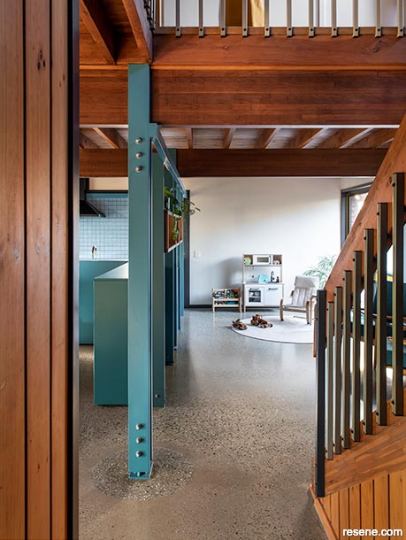 The blue kitchen complements the wooden stairwell